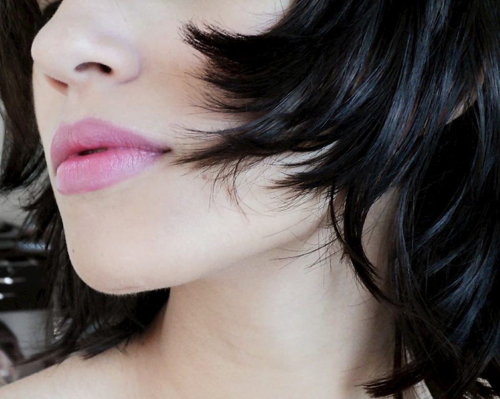 Woman with black hair and pale skin, close up on her chin and mouth.