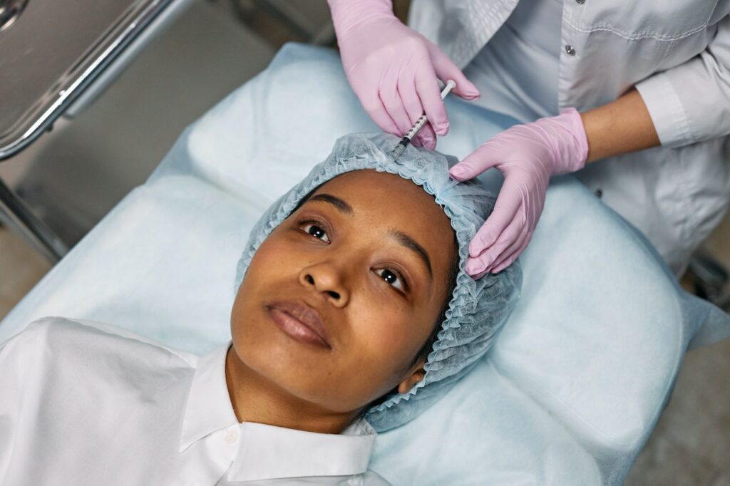 Woman lying down on a bed being injected with botox