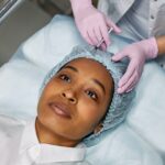 Woman lying down on a bed being injected with botox